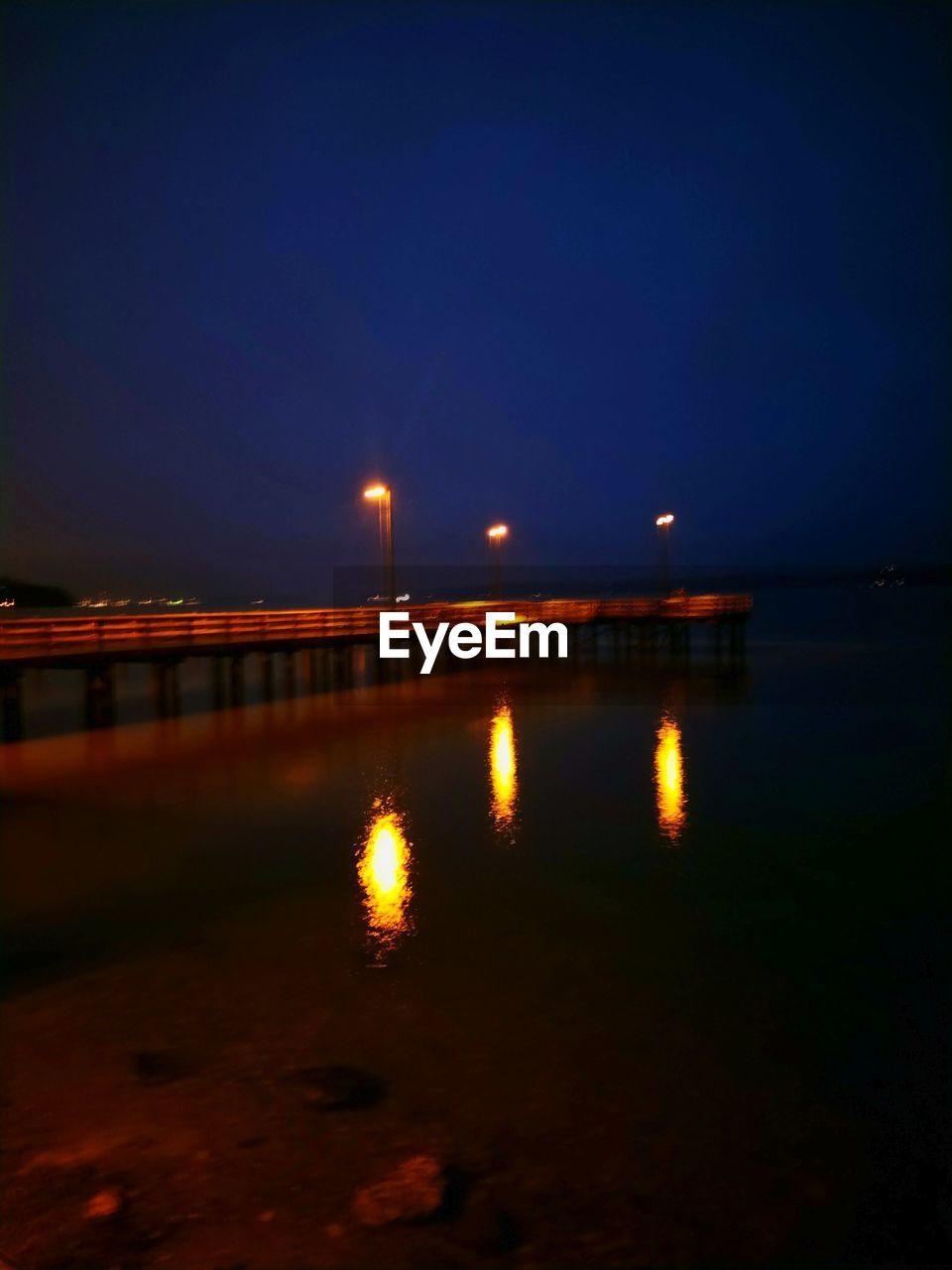 ILLUMINATED PIER OVER SEA AT NIGHT