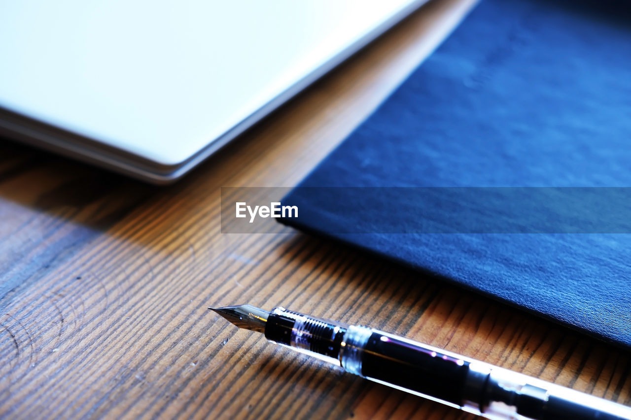 Laptop, notebook and fountain pen on wooden table - selective focus concept photo