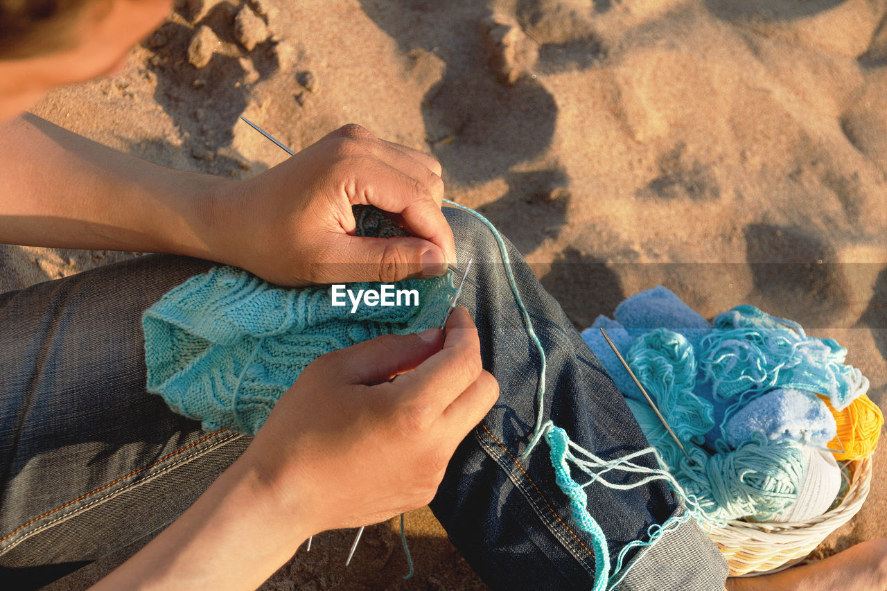 High angle view of man knitting warm clothes at beach