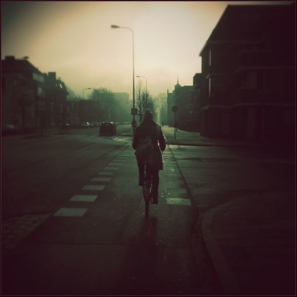 Rear view of man bicycling on road