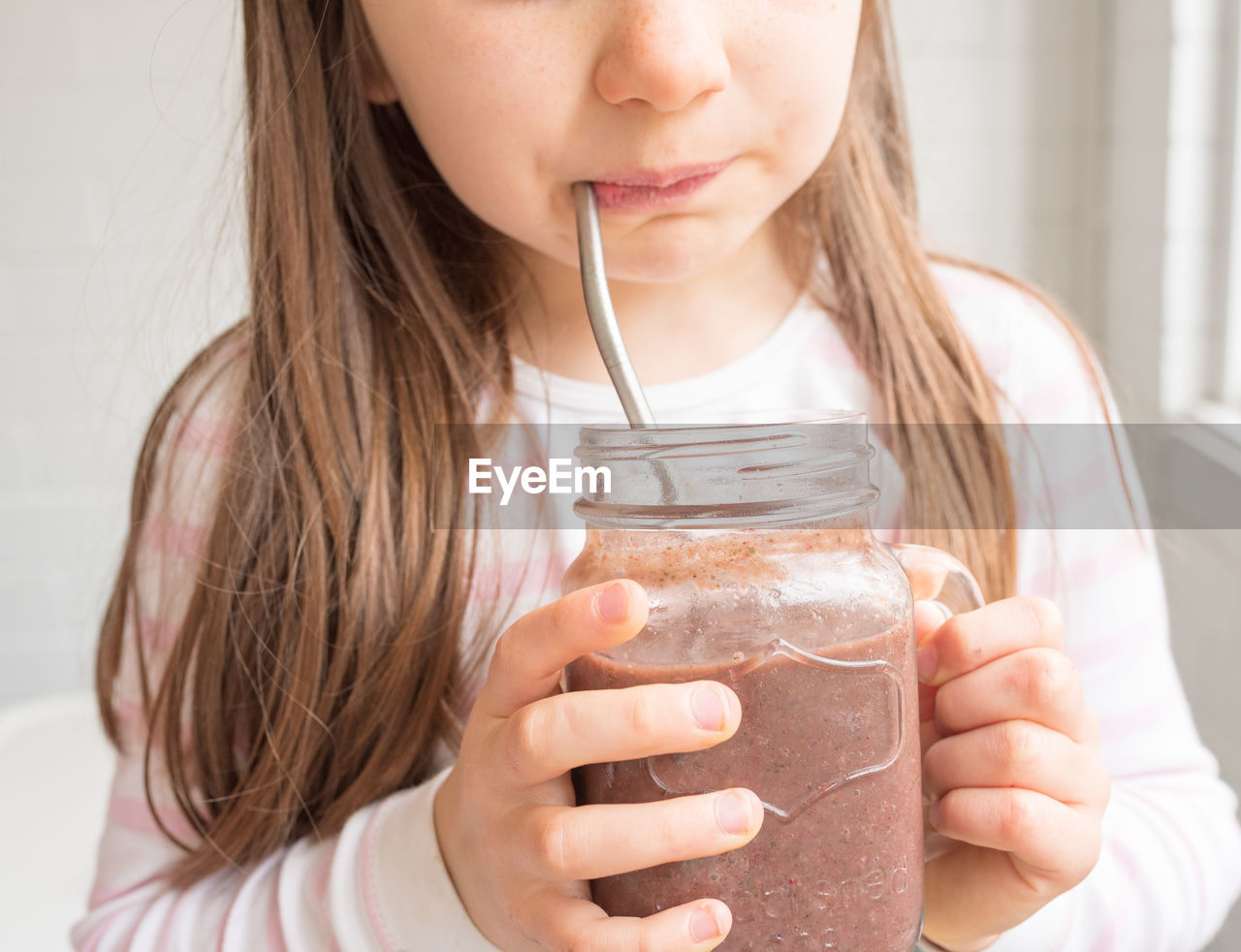 Midsection of girl drinking hot chocolate at home