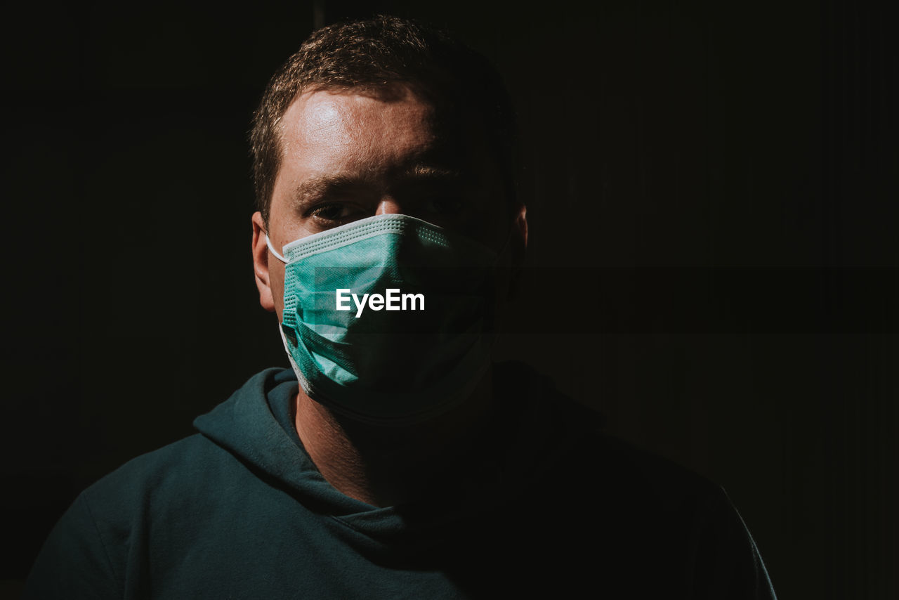 Close-up portrait of man wearing mask against black background corona covid-19