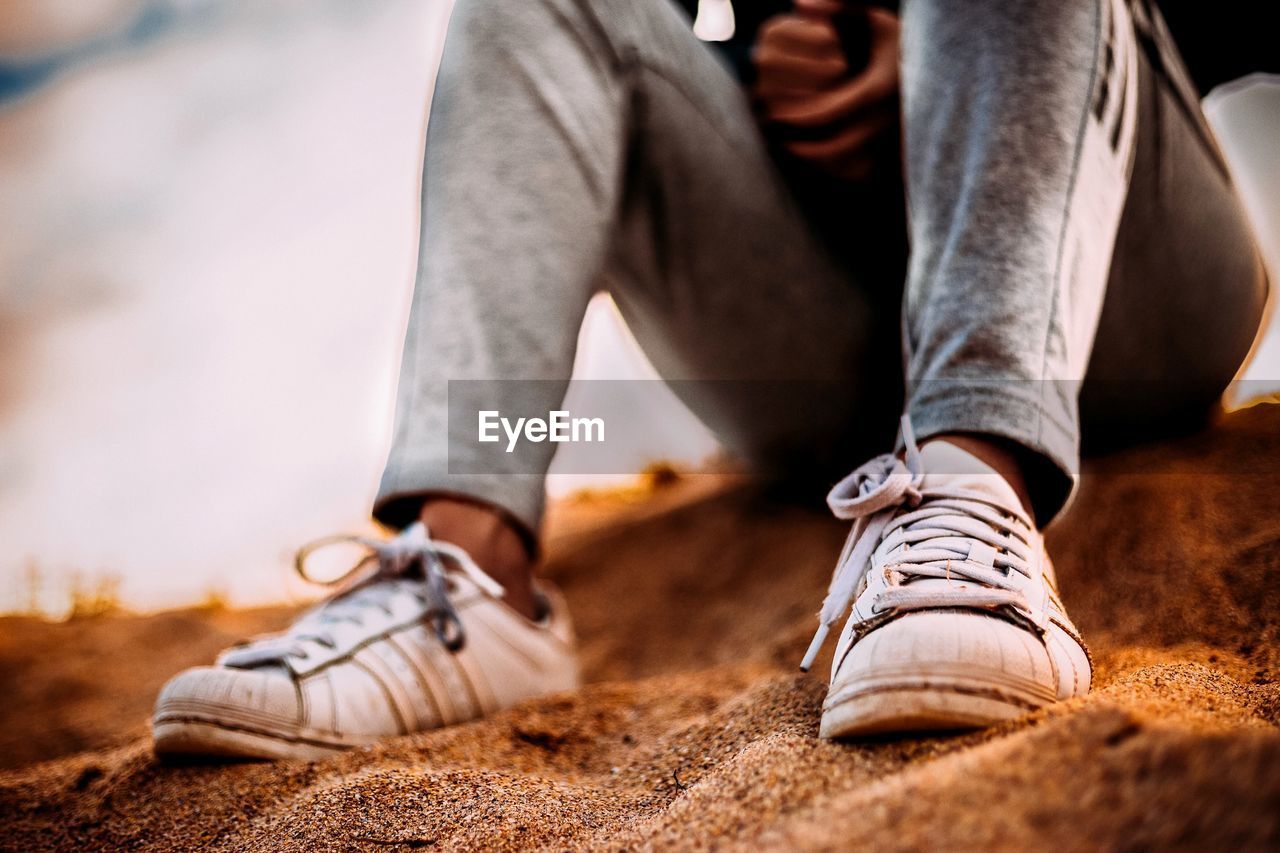 LOW SECTION OF MAN SITTING ON SHOES