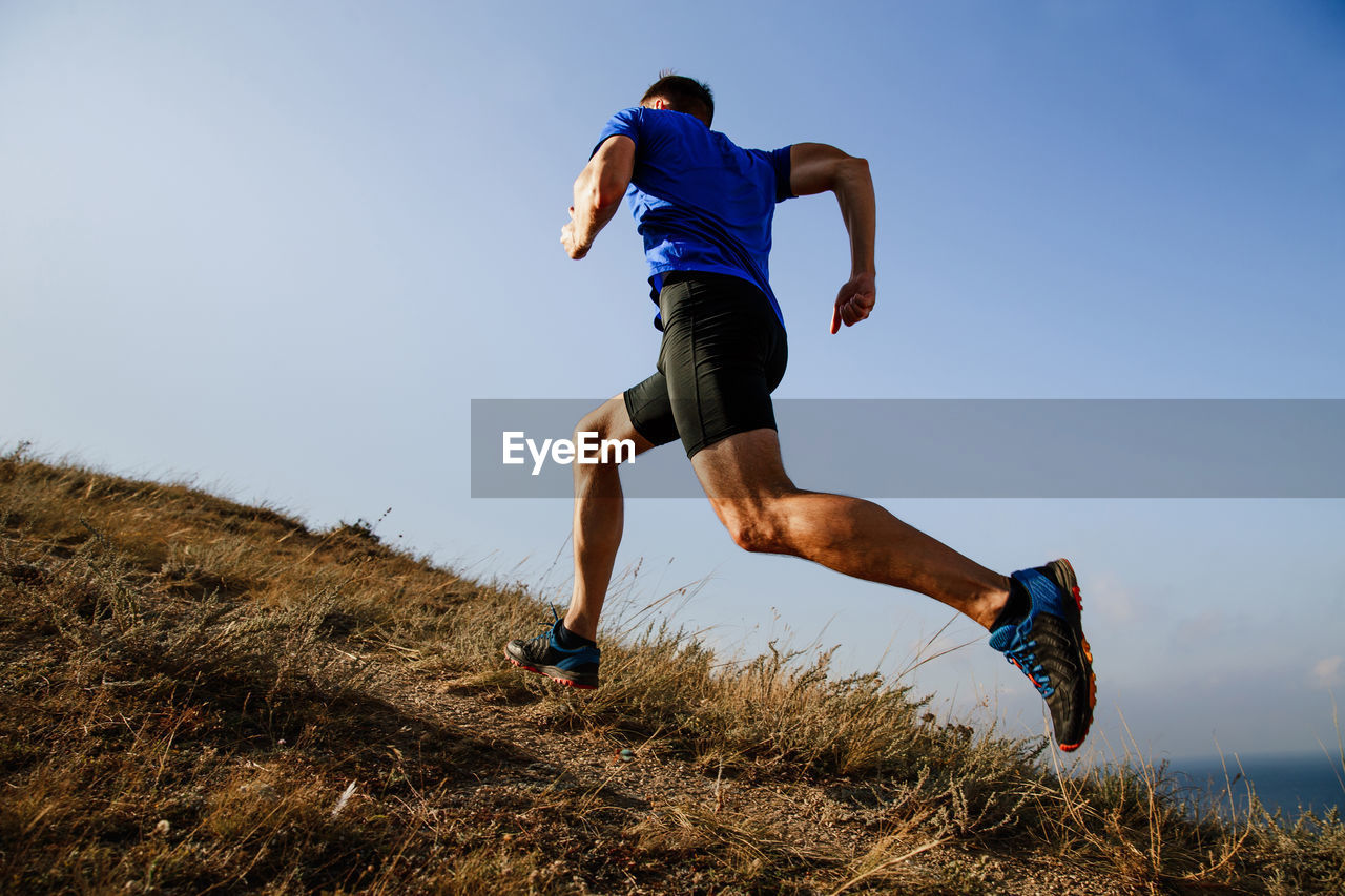 Full length of man running on hill against sky