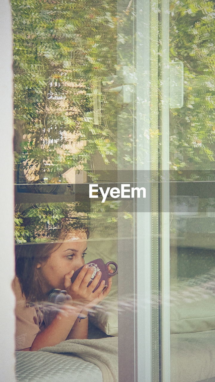 Reflection of woman photographing through window