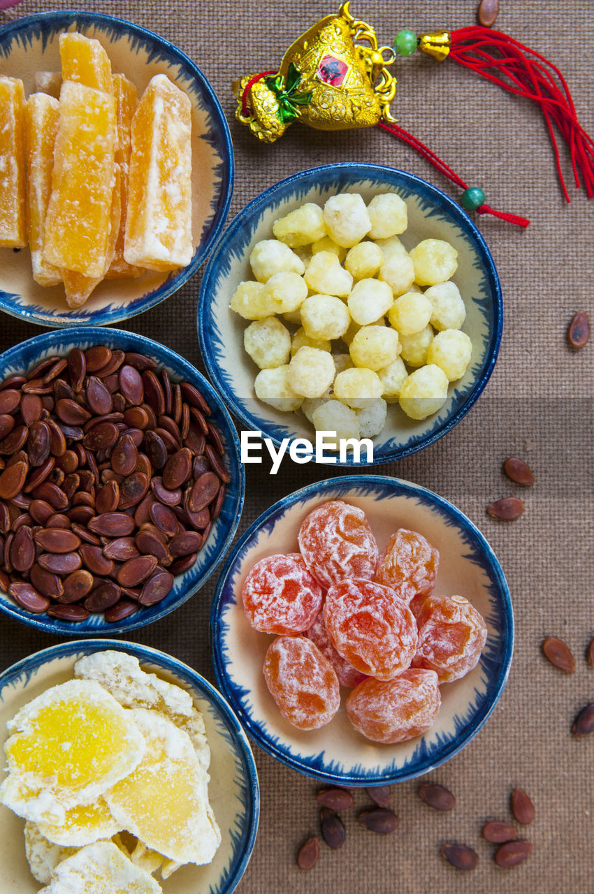 Directly above view of food in bowls with scattered seeds on table