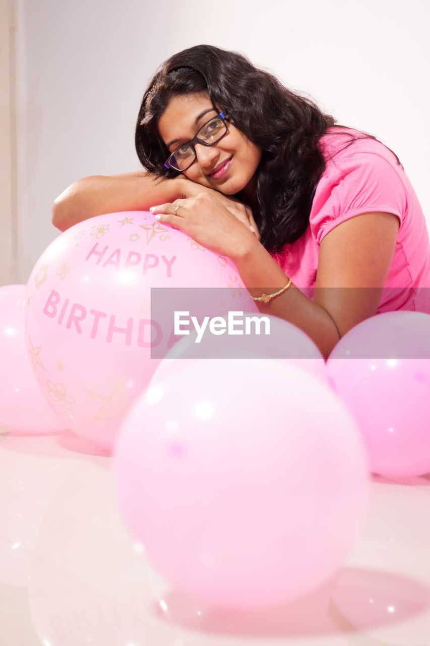 Portrait of smiling woman with pink balloons at home