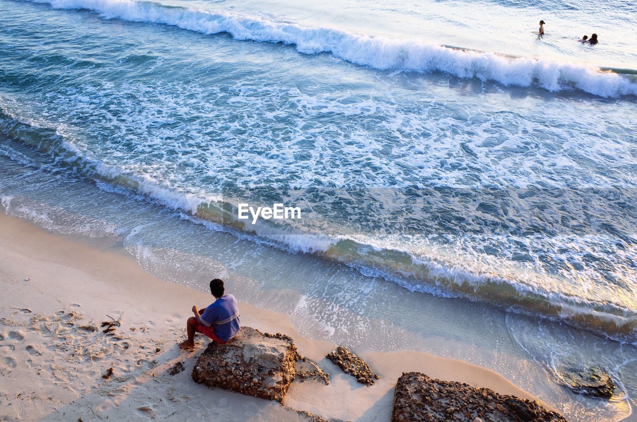 Rear view of men sitting at beach