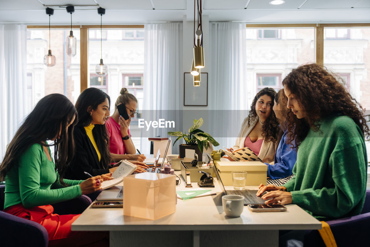 Multiracial female entrepreneurs working together while sitting at desk in office