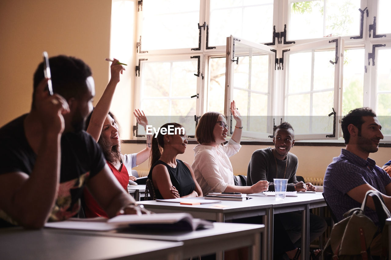 Intelligent students raising arms to answer in classroom