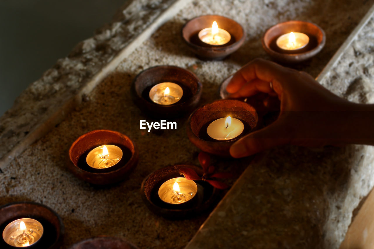 Candles light background with young woman hand taking one candle. 