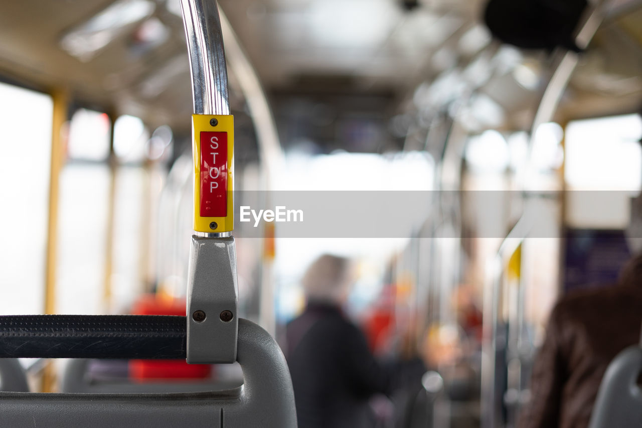 Bus interior in circulation with the stop button in the foreground on a blurred background.