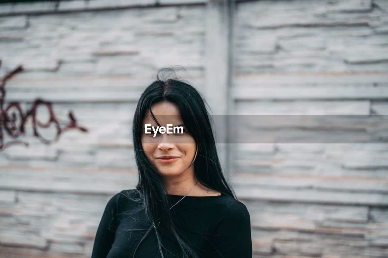 PORTRAIT OF BEAUTIFUL WOMAN STANDING AGAINST WALL