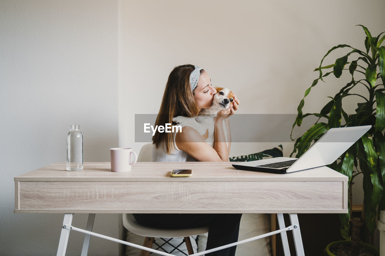 Woman embracing with dog sitting at home