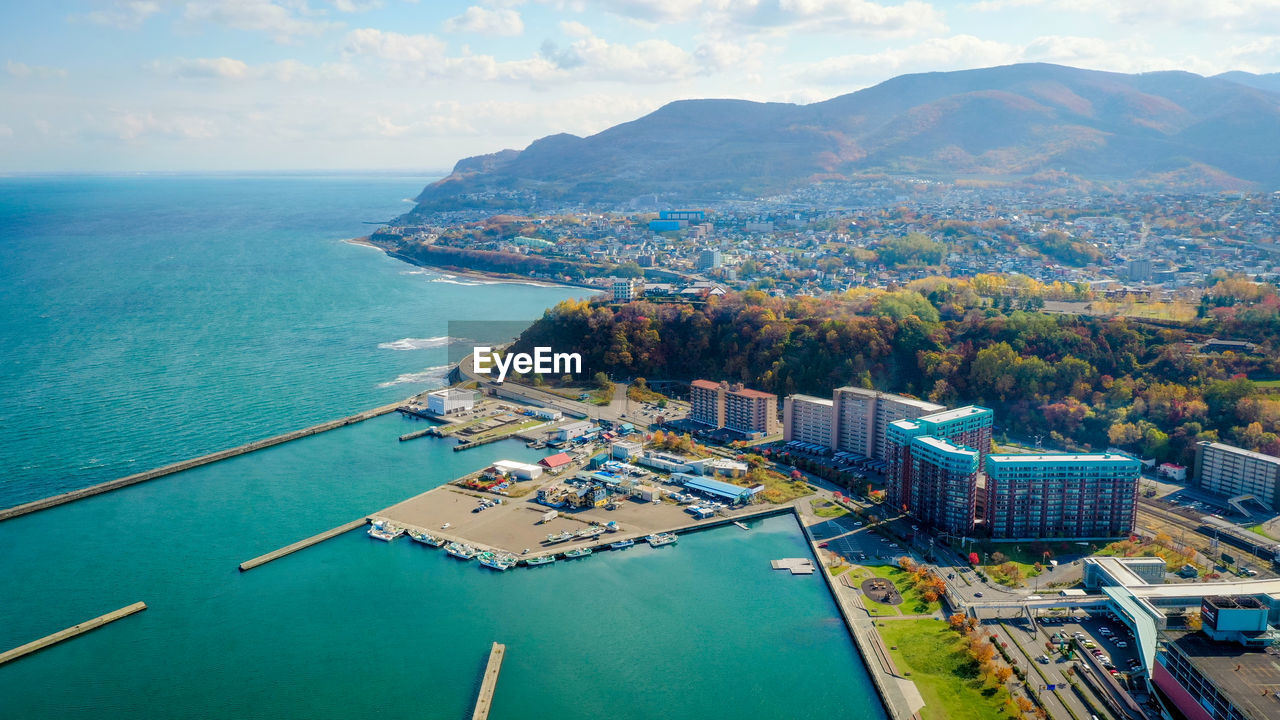 High angle view of city by sea against sky