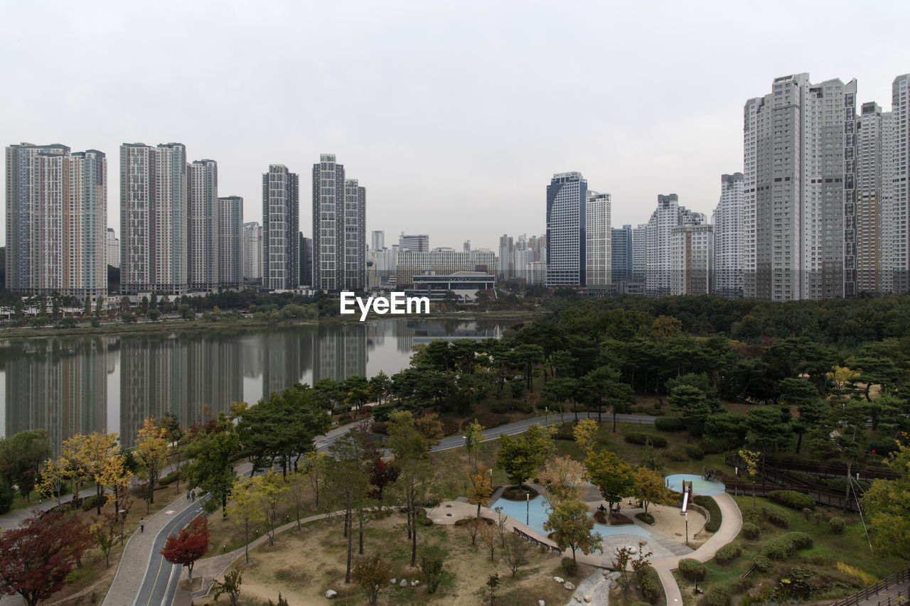 Trees and buildings in city against sky