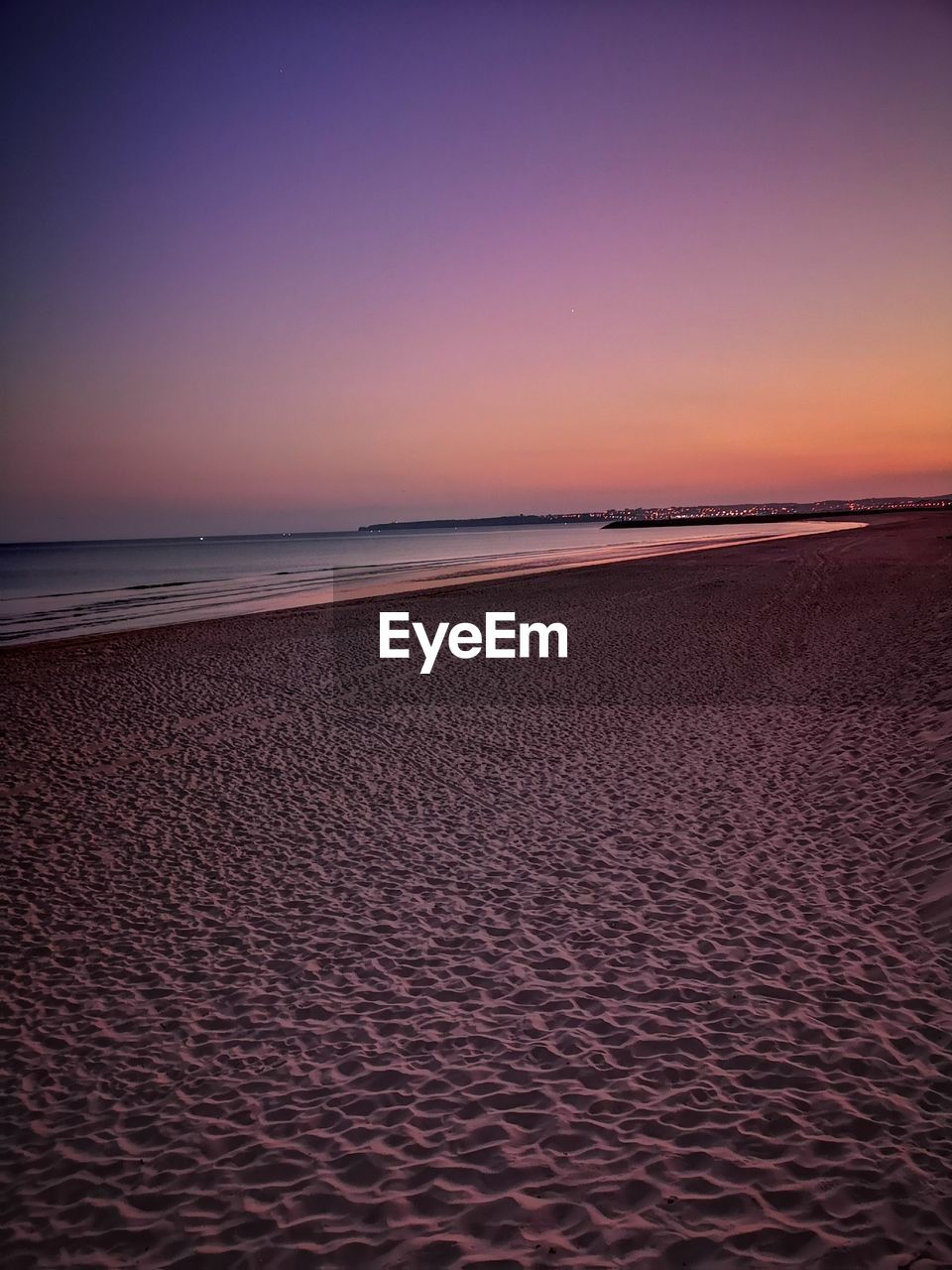 Scenic view of beach against clear sky during sunset