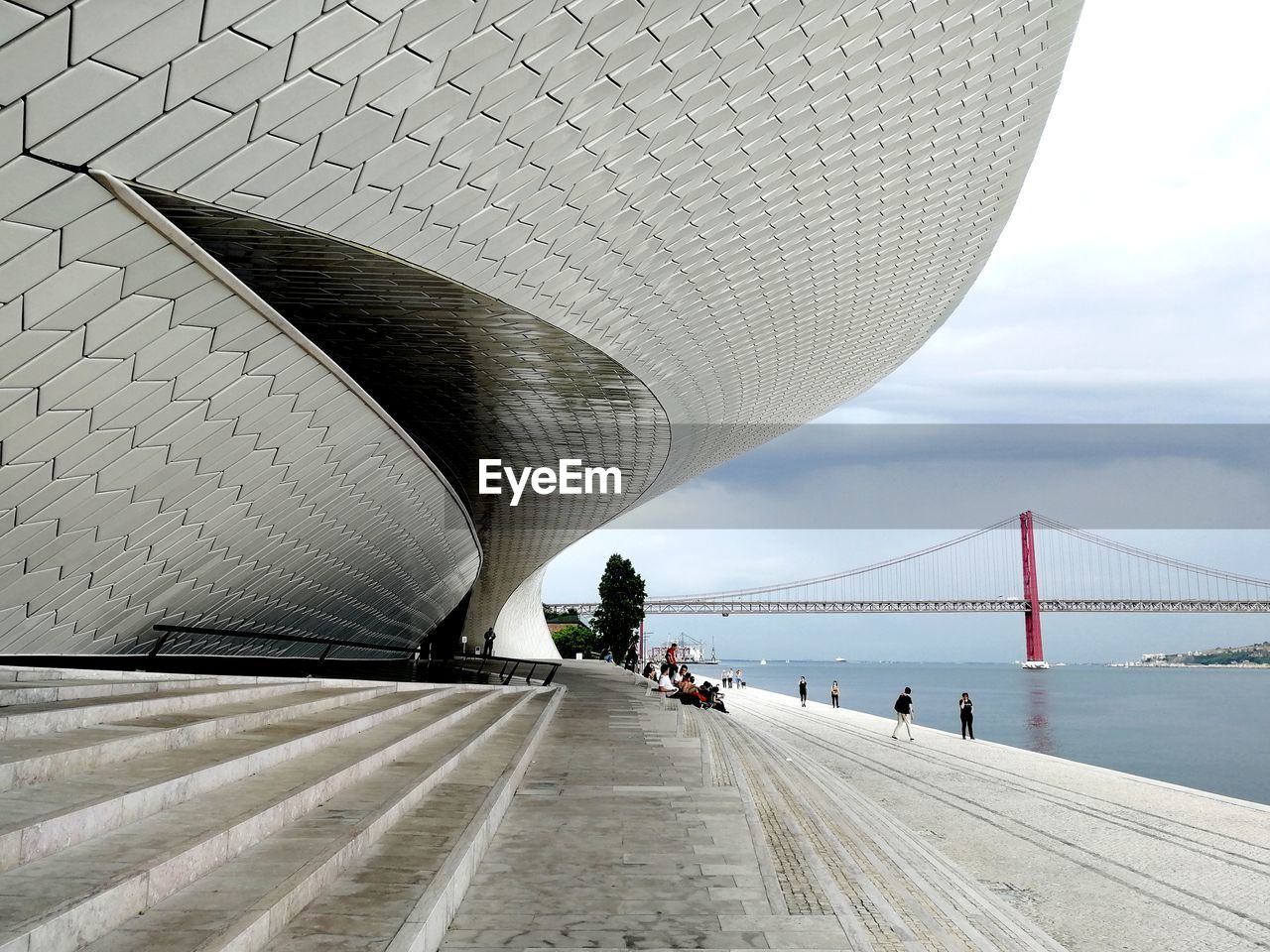 View of building entrance and bridge against cloudy sky