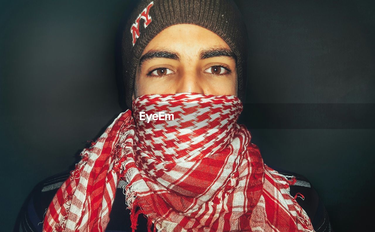 Close-up portrait of young man wearing scarf and knit hat