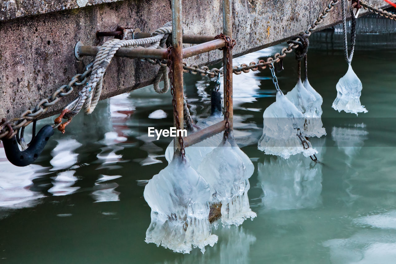 Ice covered ladder and chain of pier over lake