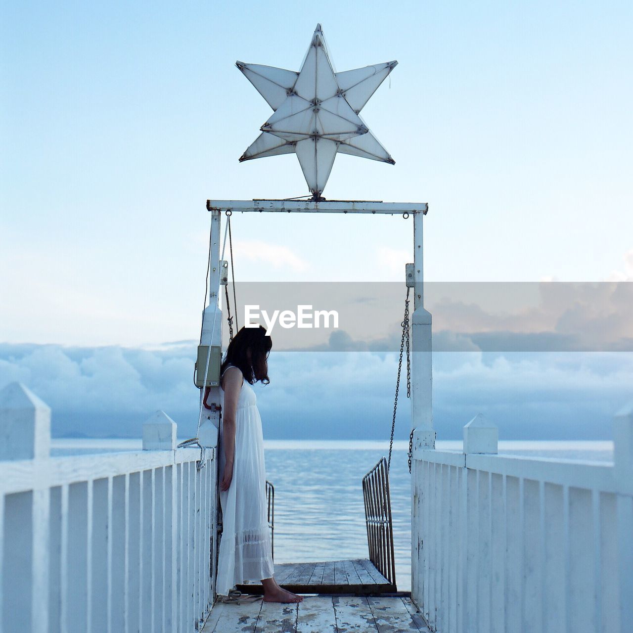 Woman standing on pier over sea against sky