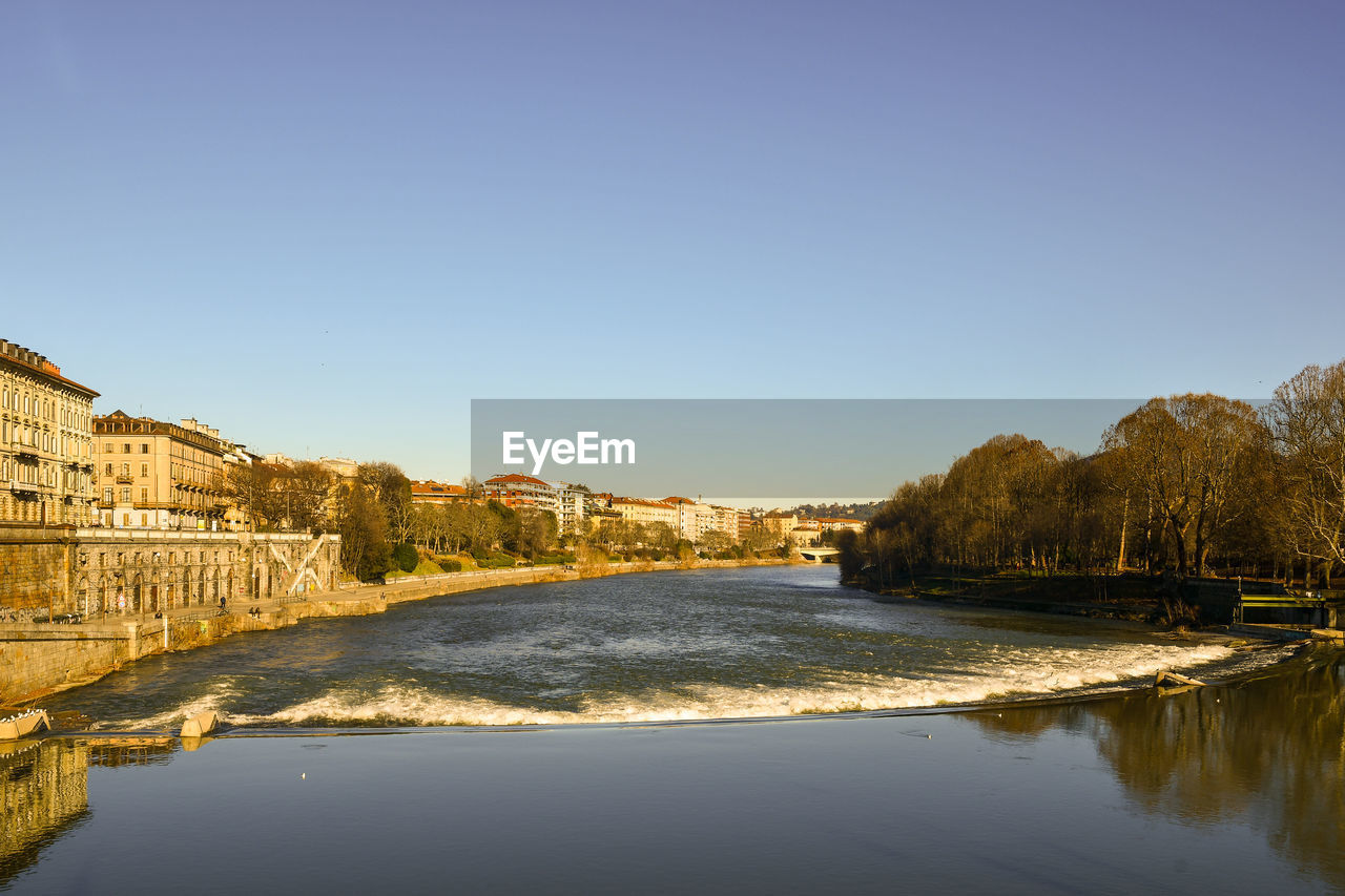 River amidst buildings against clear blue sky