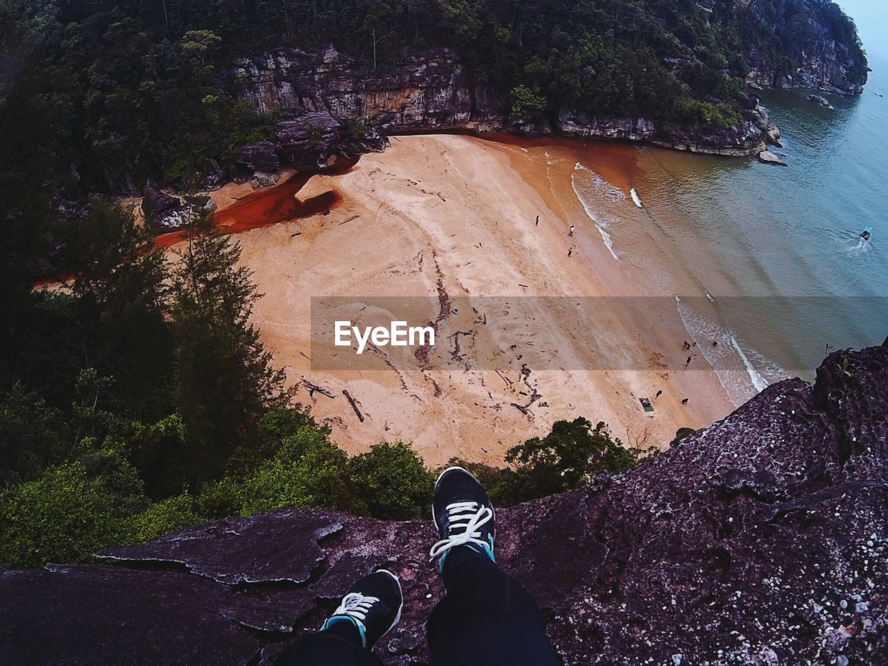 Low section of person sitting on rock against beach