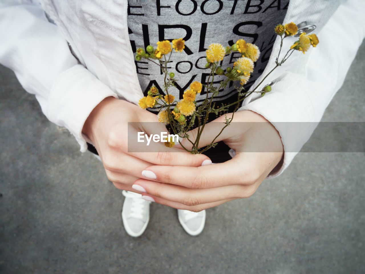 Low section of man holding yellow flowers on street