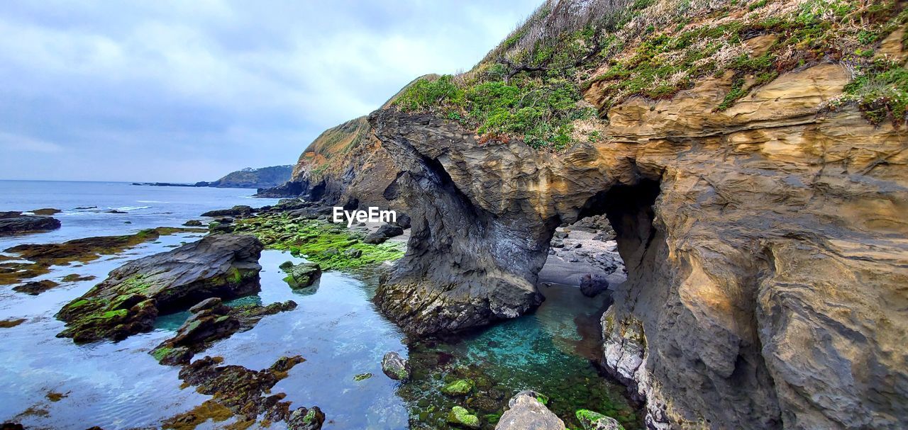 Rock formation on beach against sky