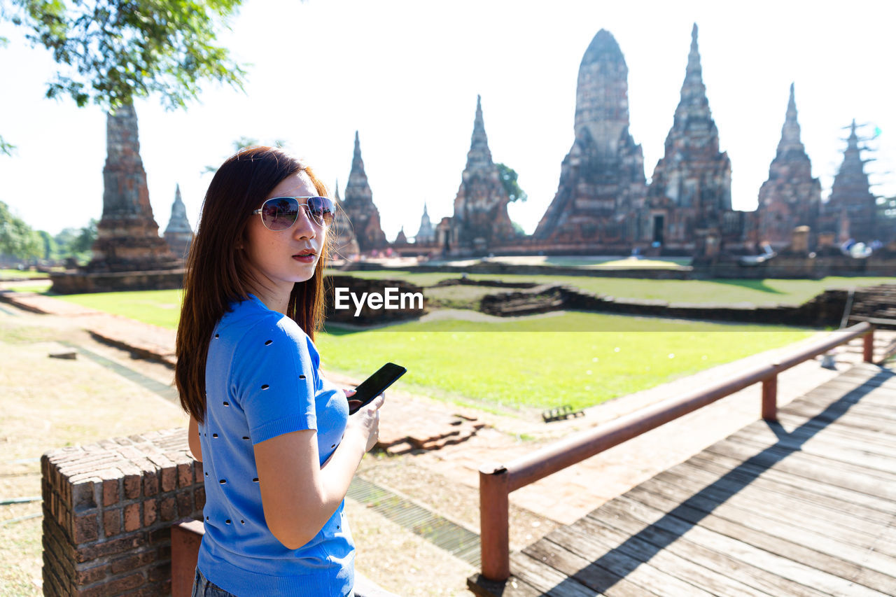 Young woman wearing sunglasses standing at temple