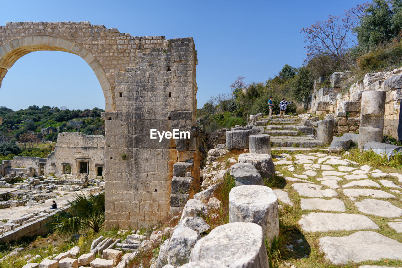 ruins, history, architecture, the past, old ruin, ancient, ancient history, built structure, historic site, travel destinations, arch, clear sky, travel, sky, fortification, nature, amphitheatre, ruined, landmark, archaeology, stone material, tourism, archaeological site, ancient civilization, old, building, aqueduct, memorial, monument, plant, rock, sunny, no people, city, wall, building exterior, vacation, damaged, blue, day, outdoors, stone wall, amphitheater