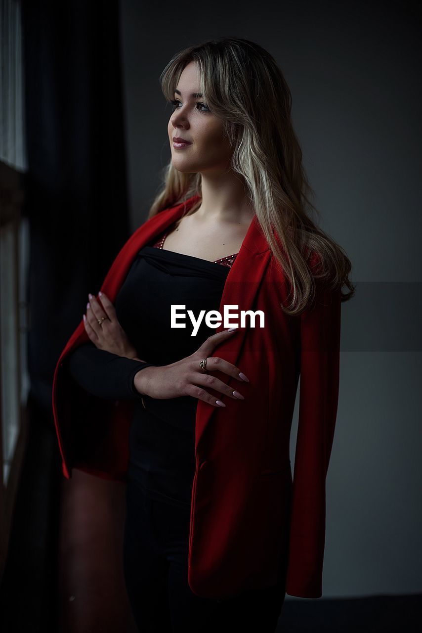 YOUNG WOMAN STANDING IN RED DRESS