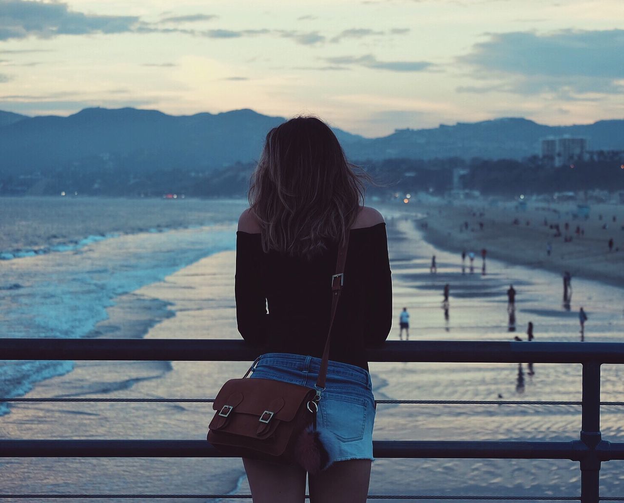 Rear view of beautiful woman on pier at beach during sunset