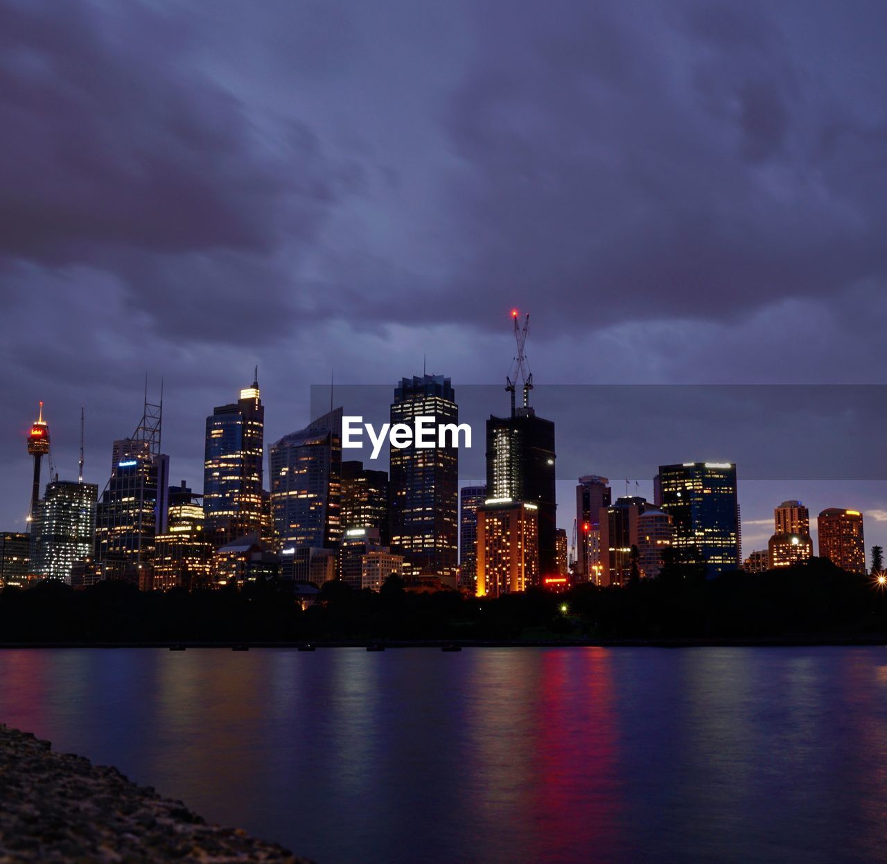 ILLUMINATED CITY BY RIVER AGAINST SKY