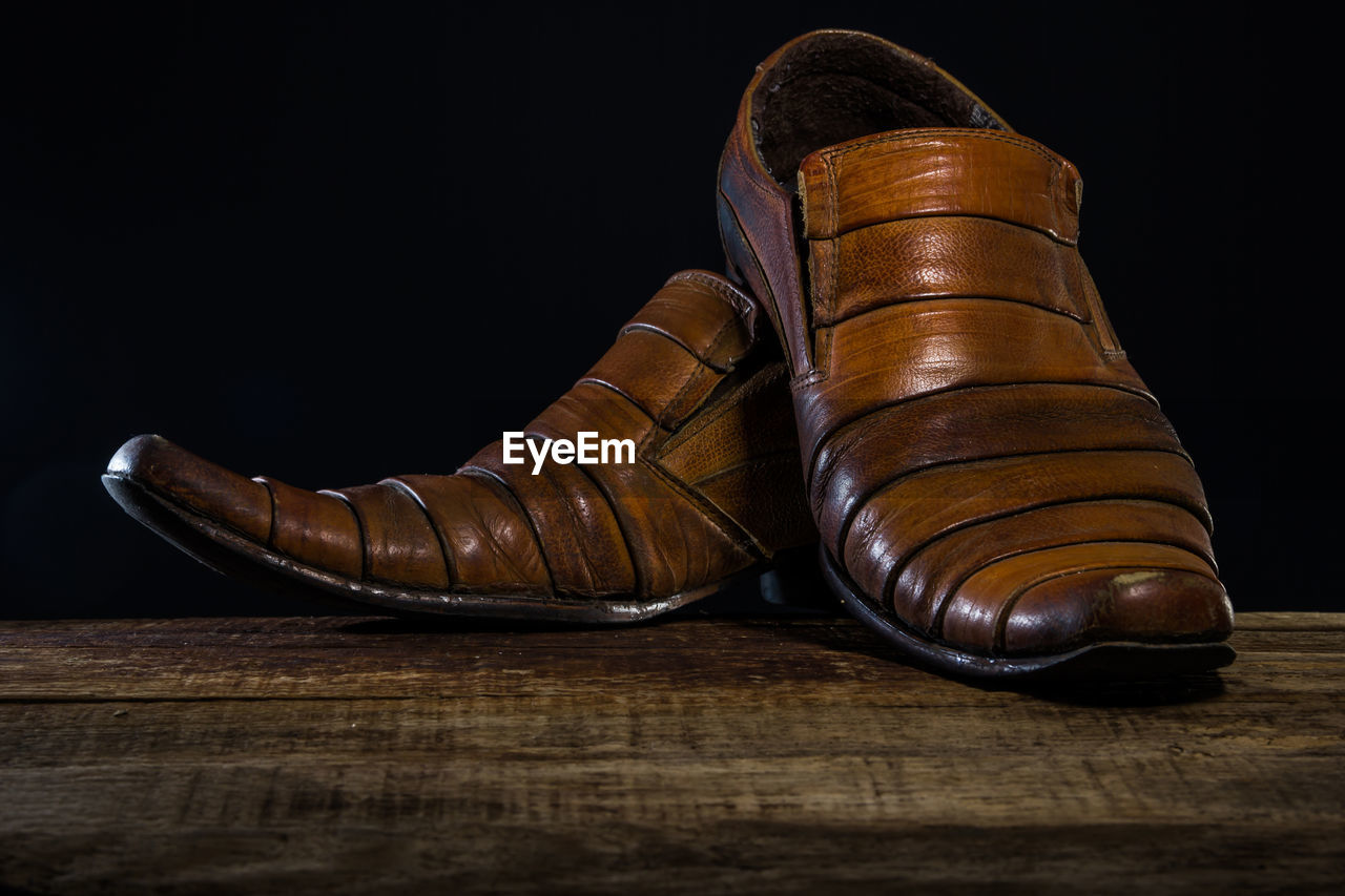 CLOSE-UP OF SHOES ON WOODEN TABLE