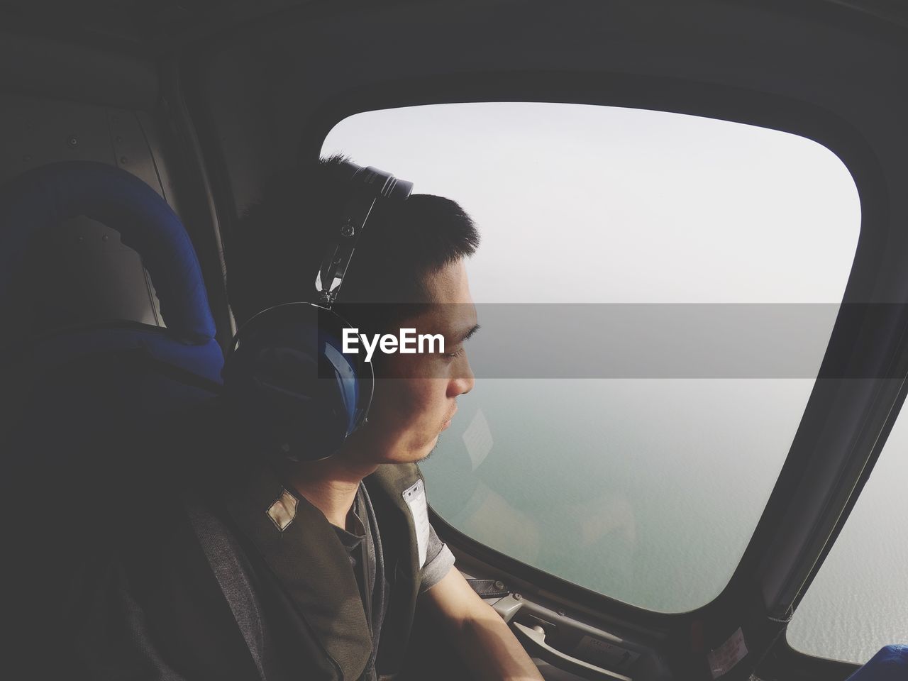 Man listening music while looking through airplane window