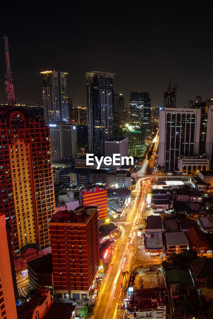 High angle view of illuminated street amidst buildings in city at night