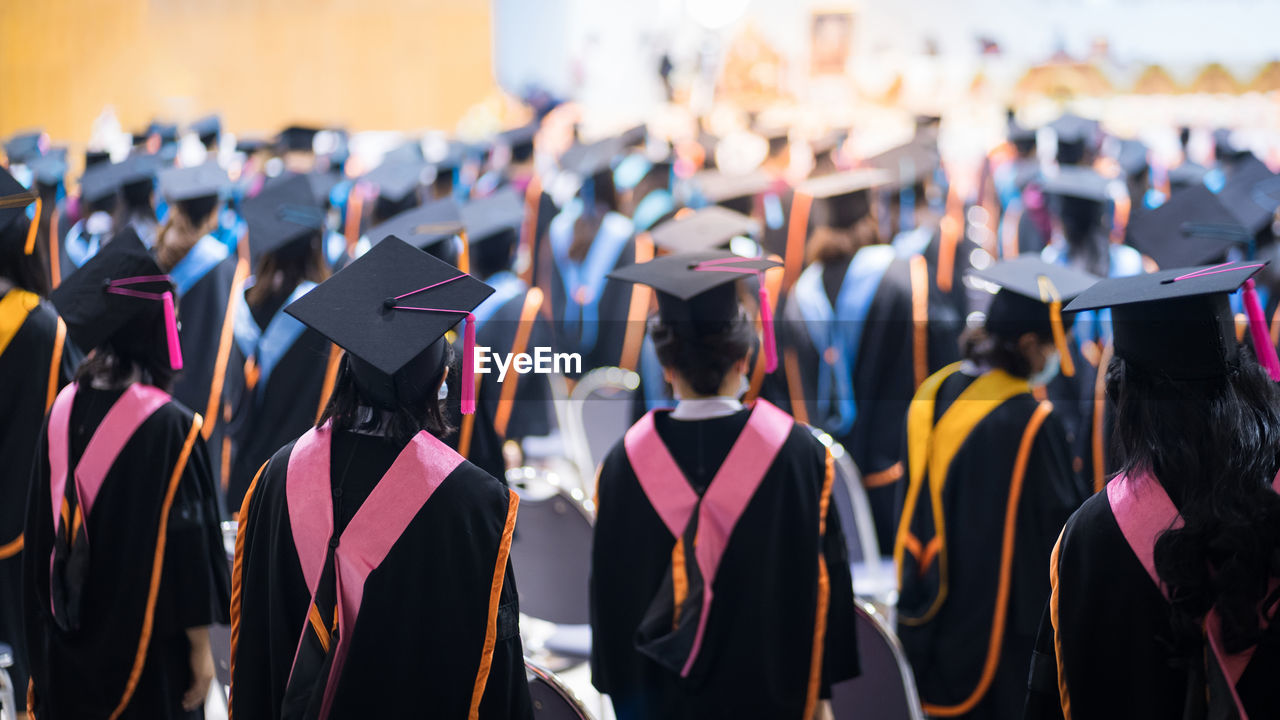 Rear view of people wearing graduation gown standing outdoors