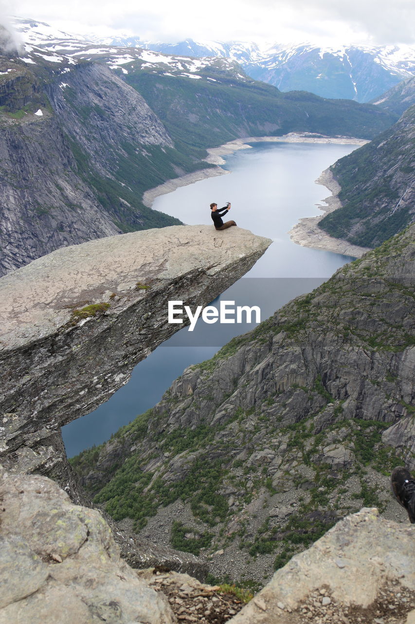 Man sitting on cliff against river