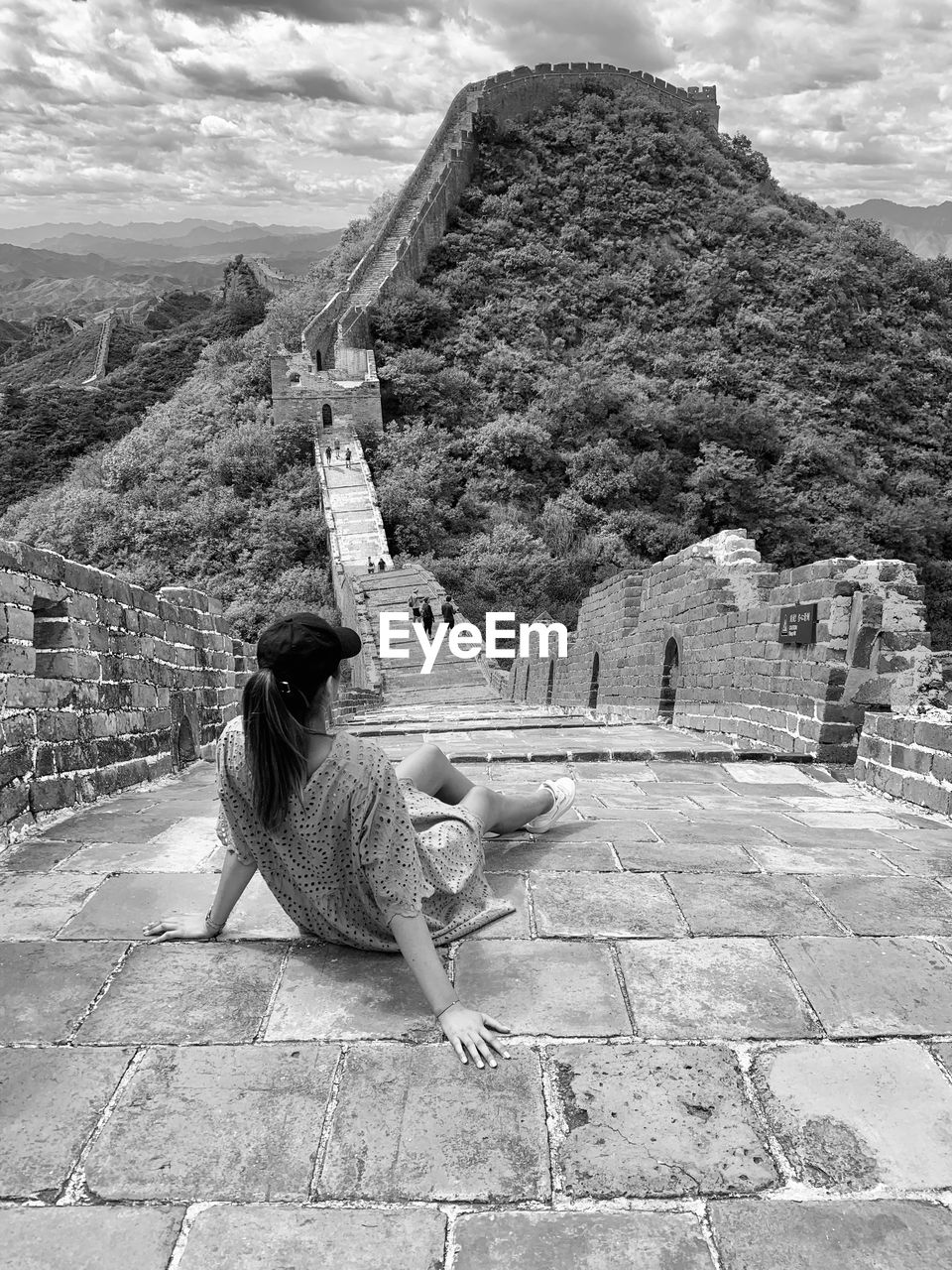 WOMAN SITTING ON STAIRCASE BY MOUNTAIN AGAINST SKY