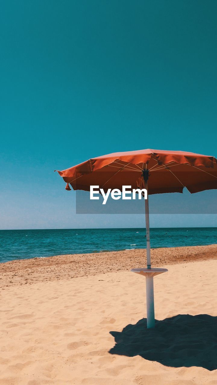 Parasol at beach against clear sky