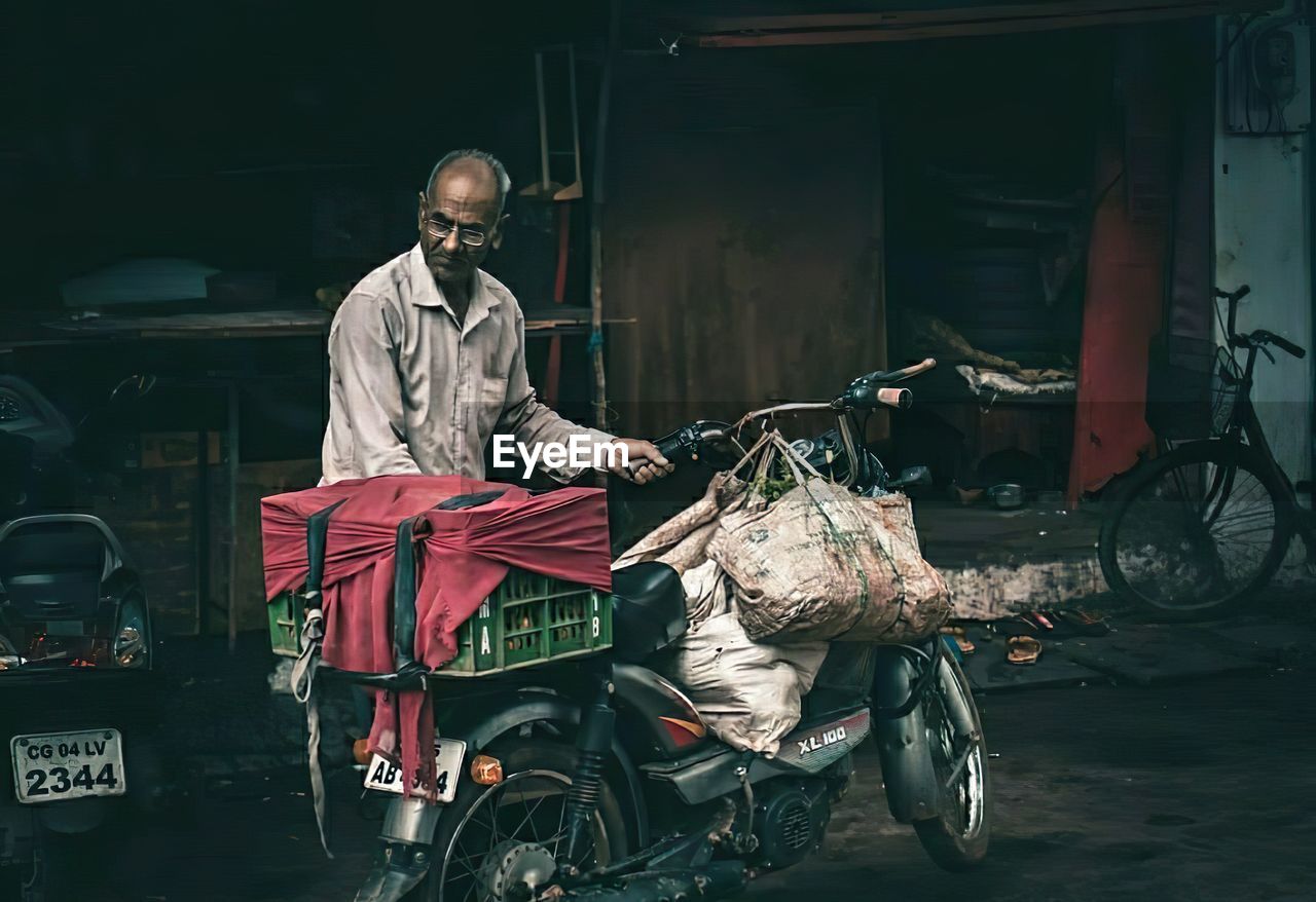 FULL LENGTH OF MAN STANDING BY BICYCLE ON CITY