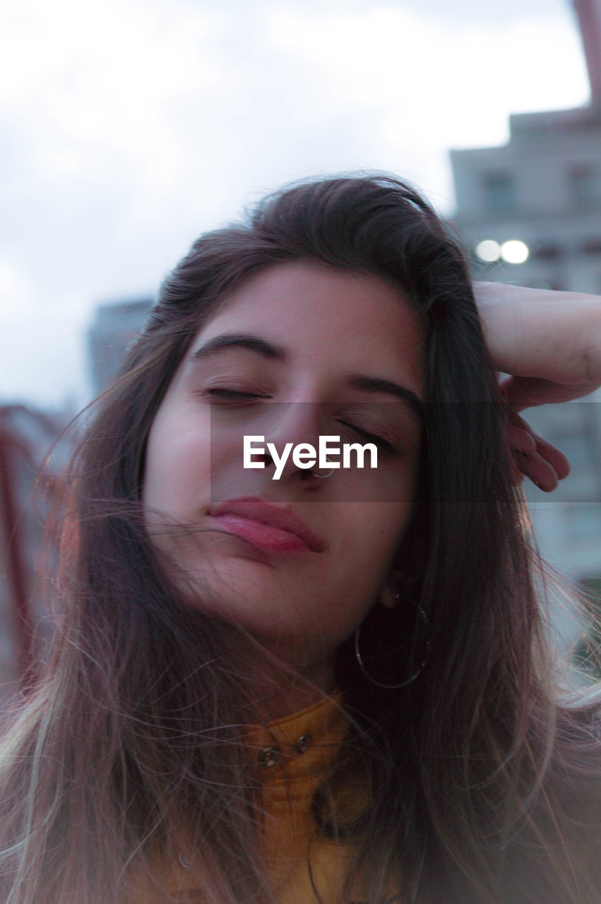 Close-up of young woman with eyes closed against sky