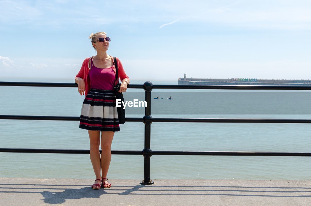 Full length of woman standing on pier over sea against sky