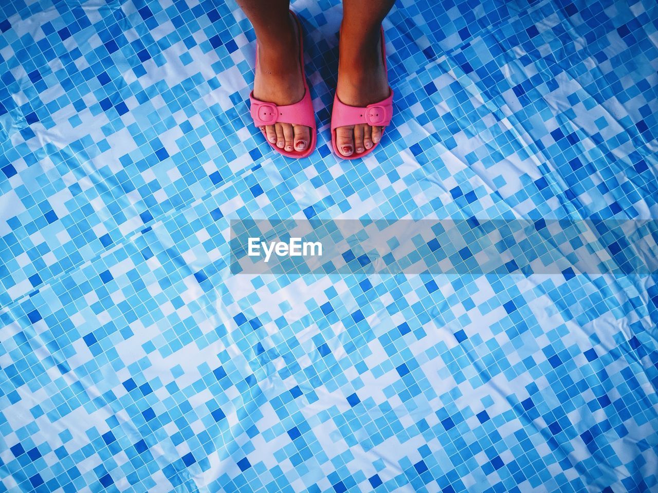 LOW SECTION VIEW OF WOMAN STANDING ON SWIMMING POOL