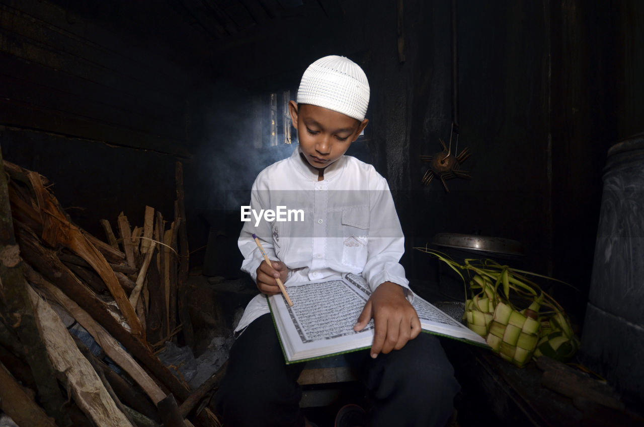 Close-up of boy reading koran in darkroom