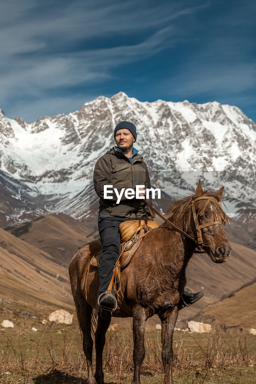 rear view of man riding horse on snowcapped mountain