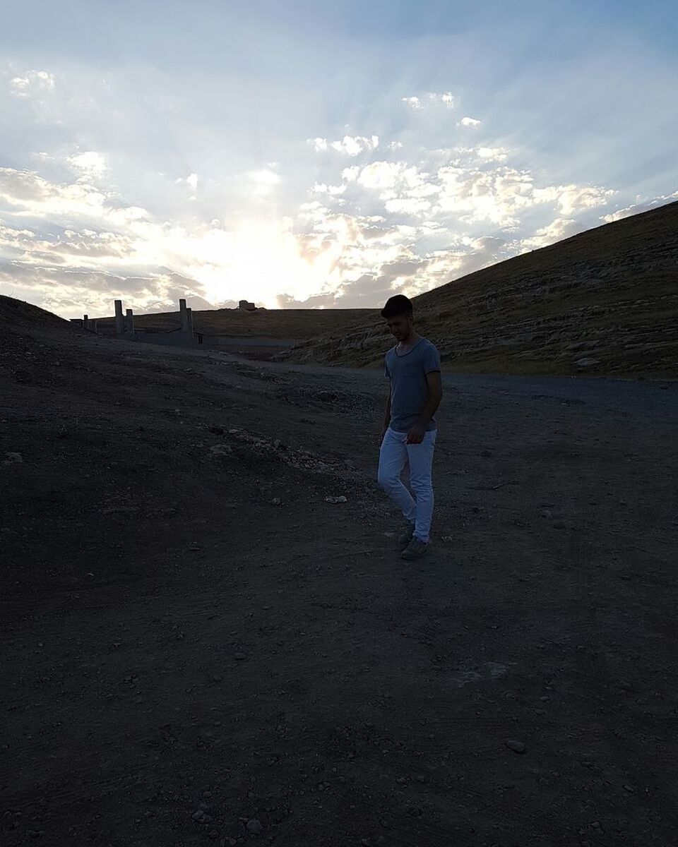 WOMAN STANDING ON FIELD AGAINST MOUNTAIN