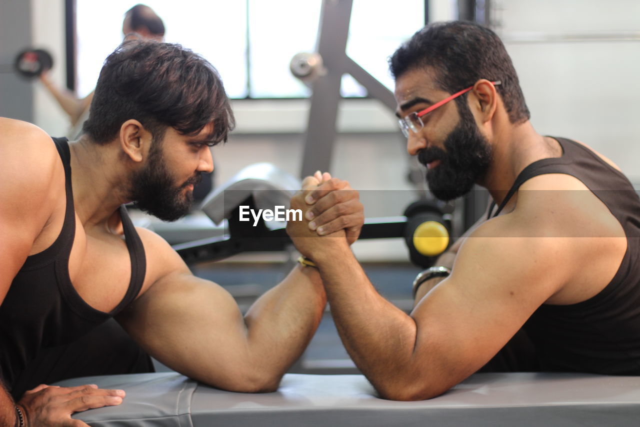 Male friends arm wrestling at gym