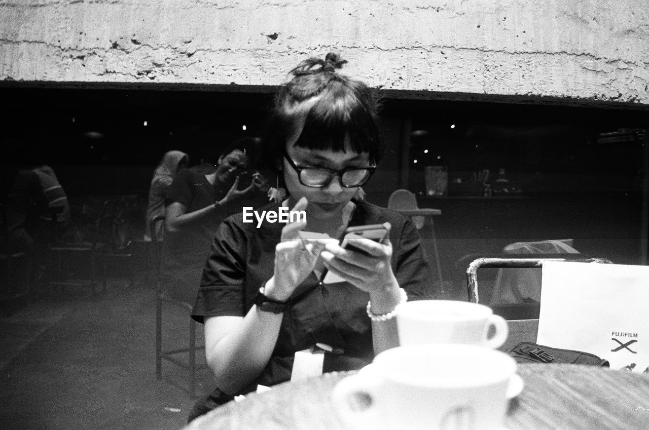 PORTRAIT OF WOMAN SITTING AT RESTAURANT TABLE IN CAFE